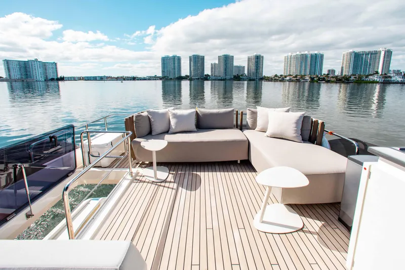 Our Trade Yacht Photos Pics Luxurious 2022 Ferretti Yachts 670 deck with modern seating, overlooking serene waterfront cityscape.