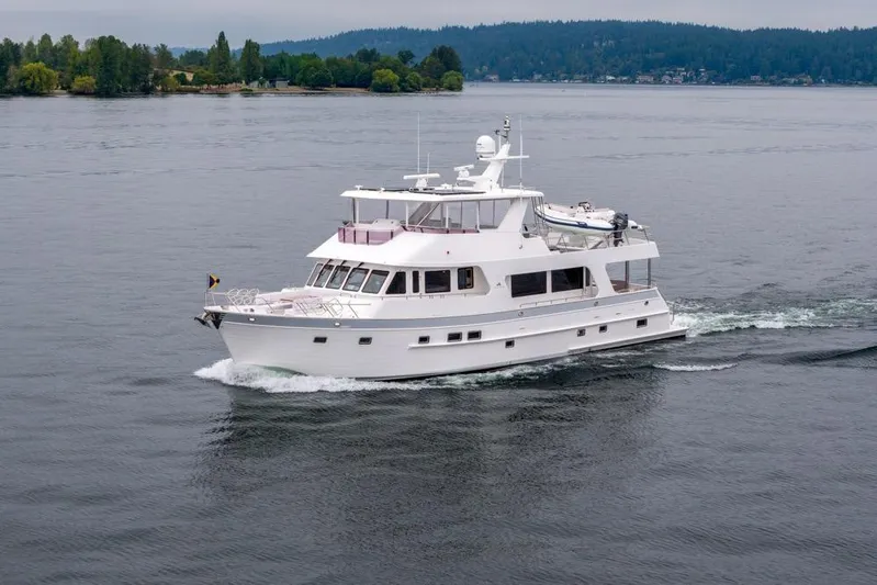 Smile Smile Smile Yacht Photos Pics 2022 Outer Reef 720 Motor Yacht cruising on a serene lake with lush green shoreline.