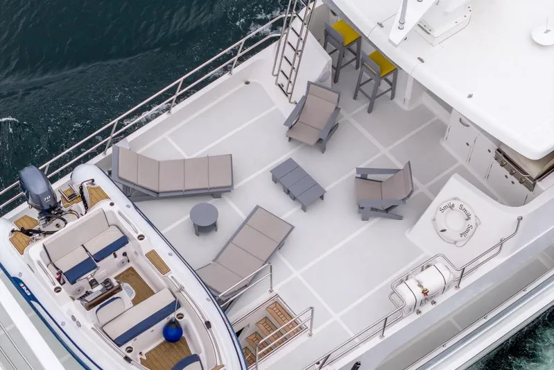 Smile Smile Smile Yacht Photos Pics Aerial view of 2022 Outer Reef 720 Motor Yacht deck with seating and small boat.