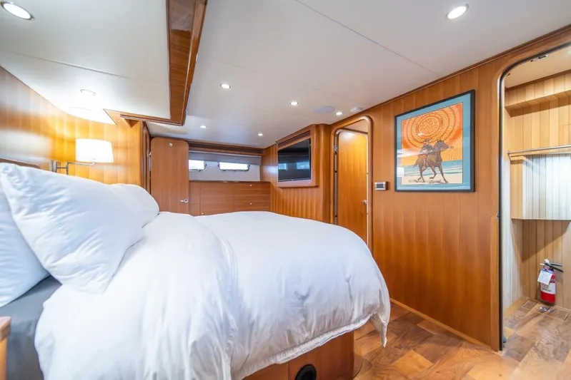 Smile Smile Smile Yacht Photos Pics Luxurious bedroom interior of 2022 Outer Reef 720 Motor Yacht with wood paneling and artwork.