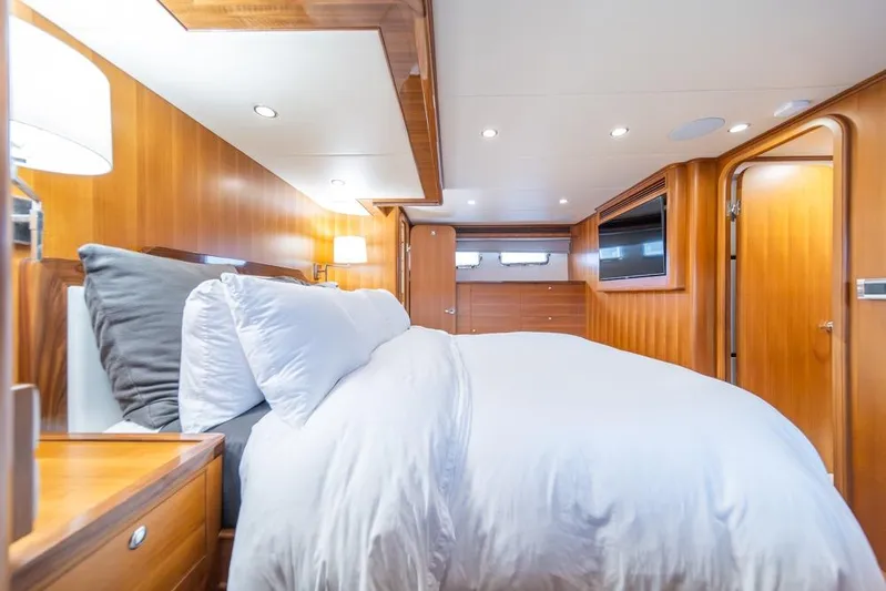 Smile Smile Smile Yacht Photos Pics Luxurious bedroom interior of 2022 Outer Reef 720 Motor Yacht with wood paneling and cozy bedding.