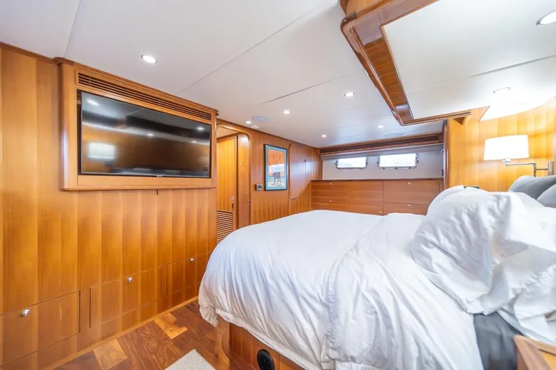 Smile Smile Smile Yacht Photos Pics Luxurious bedroom interior of 2022 Outer Reef 720 Motor Yacht with wood paneling and TV.