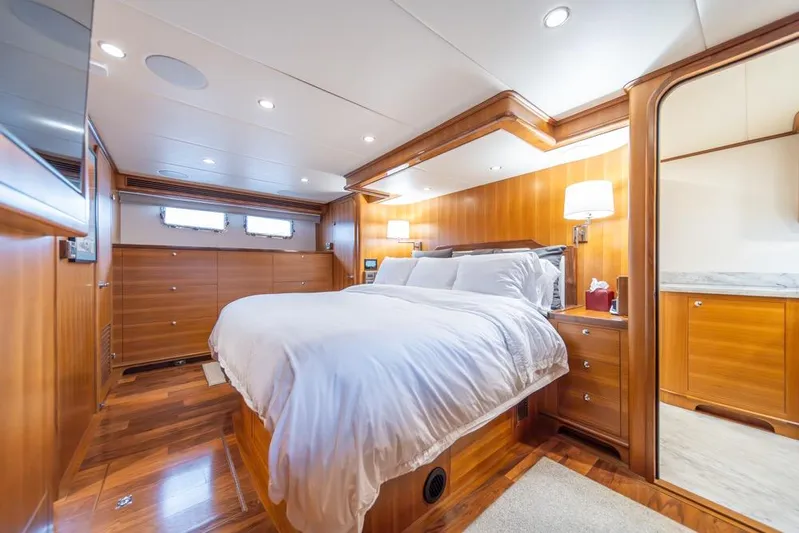 Smile Smile Smile Yacht Photos Pics Luxurious bedroom interior of 2022 Outer Reef 720 Motor Yacht with wood paneling and cozy lighting.