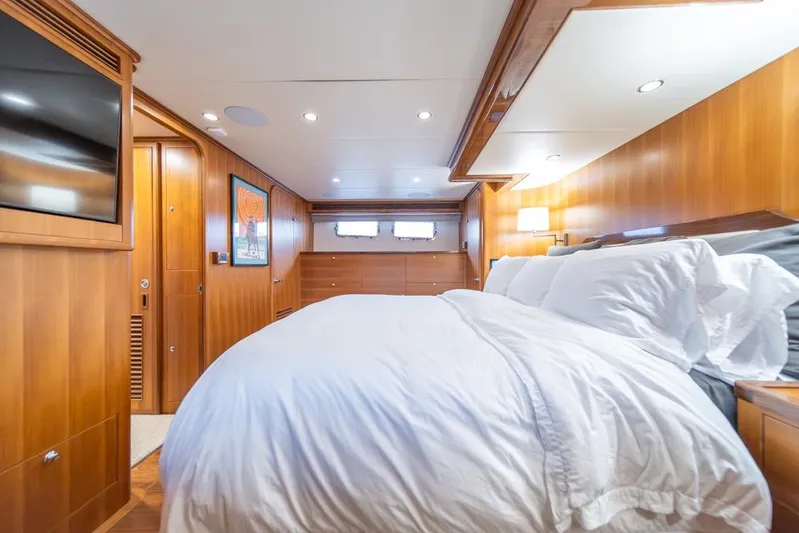 Smile Smile Smile Yacht Photos Pics Luxurious bedroom interior of 2022 Outer Reef 720 Motor Yacht with wood paneling and cozy bedding.