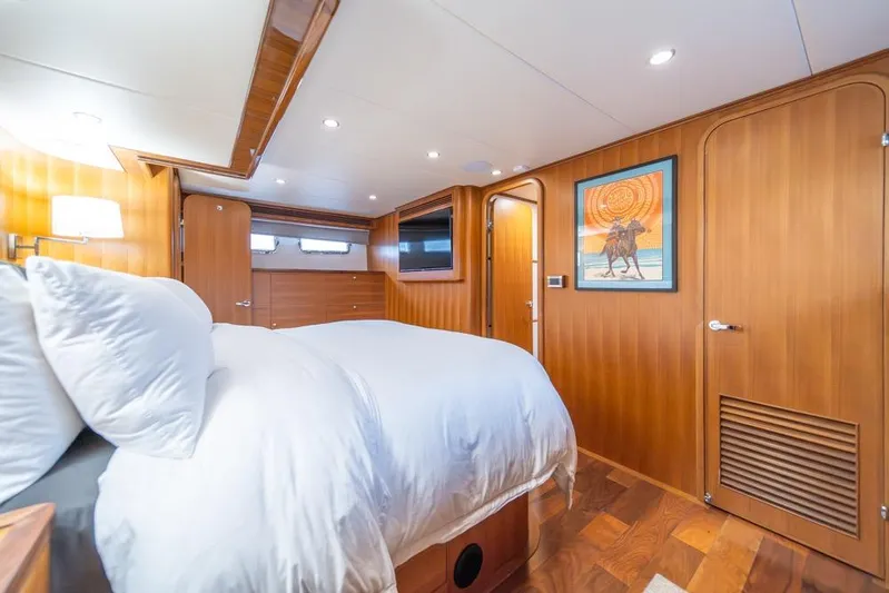 Smile Smile Smile Yacht Photos Pics Luxurious bedroom interior of 2022 Outer Reef 720 Motor Yacht with wood paneling and modern decor.