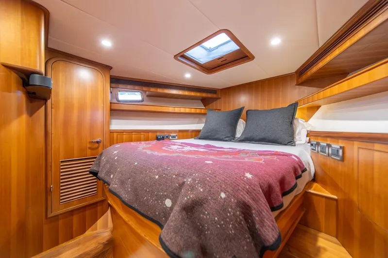 Smile Smile Smile Yacht Photos Pics Luxurious cabin interior of 2022 Outer Reef 720 Motor Yacht with wood paneling and cozy bedding.