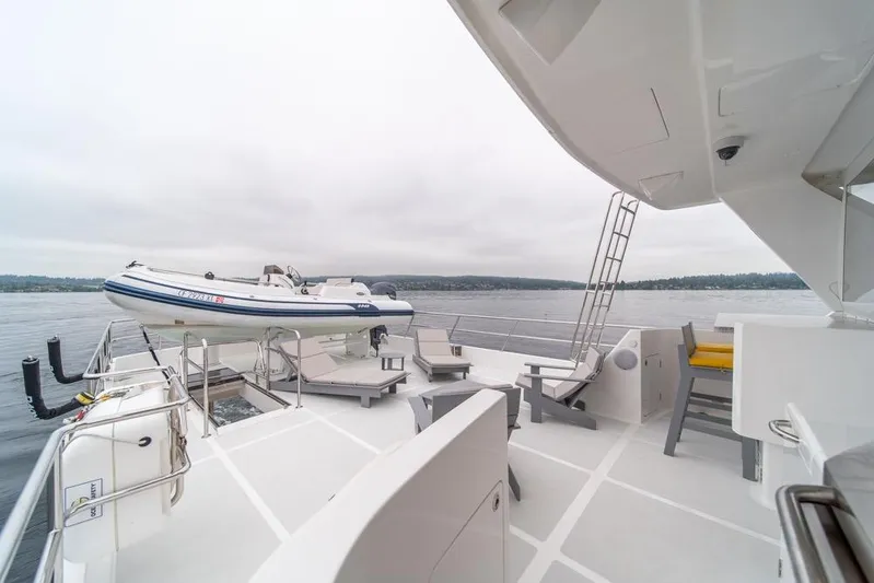 Smile Smile Smile Yacht Photos Pics Outer Reef 720 Motor Yacht 2022 deck with seating and tender boat on calm waters.