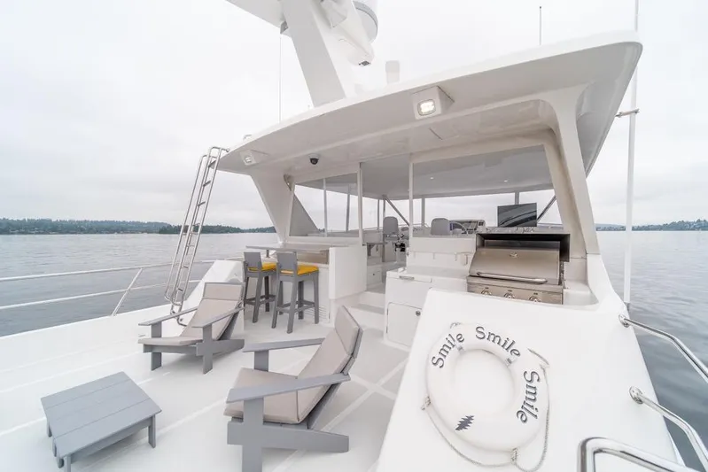 Smile Smile Smile Yacht Photos Pics Luxurious 2022 Outer Reef 720 Motor Yacht deck with seating and grill, on calm waters.