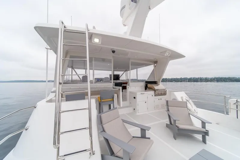 Smile Smile Smile Yacht Photos Pics 2022 Outer Reef 720 Motor Yacht deck with seating and grill, overlooking calm waters.