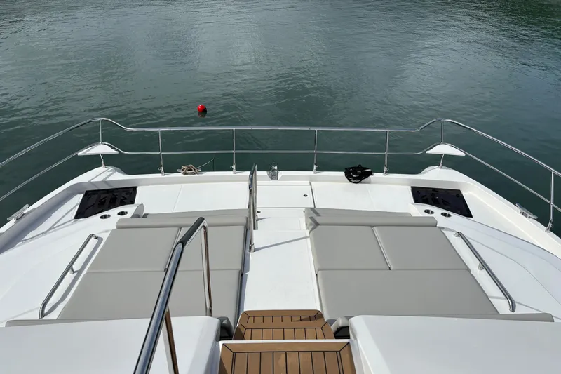  Yacht Photos Pics Aquila 54 Yacht 2025 deck with sun loungers and railing, overlooking calm water.