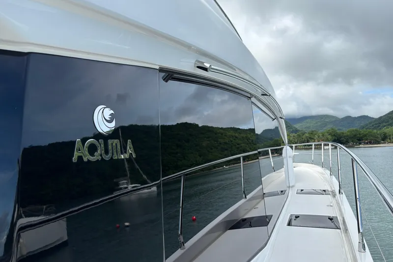  Yacht Photos Pics Aquila 54 Yacht 2025 reflecting scenic landscape on sleek exterior.