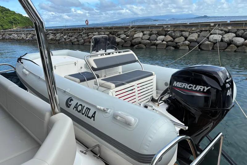  Yacht Photos Pics 2025 Aquila 54 Yacht with Mercury engine docked by rocky shoreline.