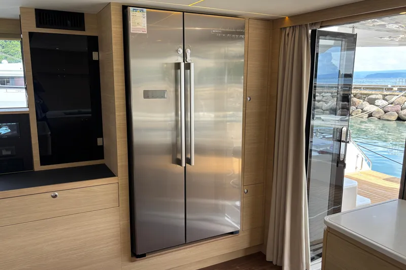  Yacht Photos Pics Modern kitchen interior on 2025 Aquila 54 Yacht with stainless steel fridge and outdoor view.