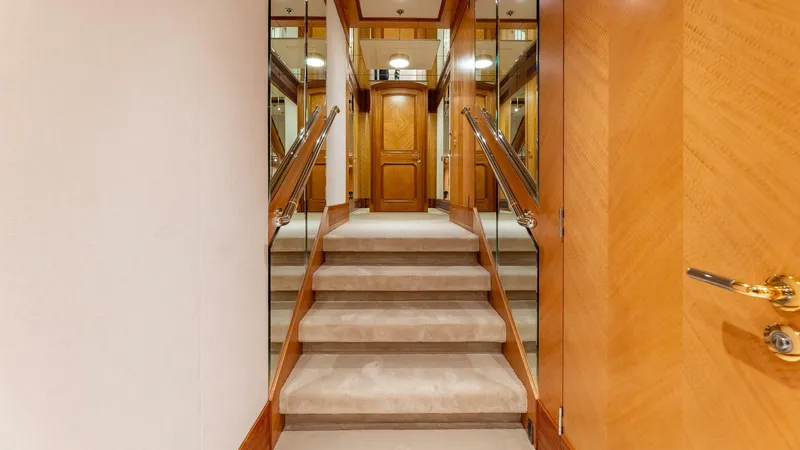 Amanti Yacht Photos Pics Luxurious interior staircase of 2003 Feadship 51.8M yacht with wooden accents and mirrored walls.