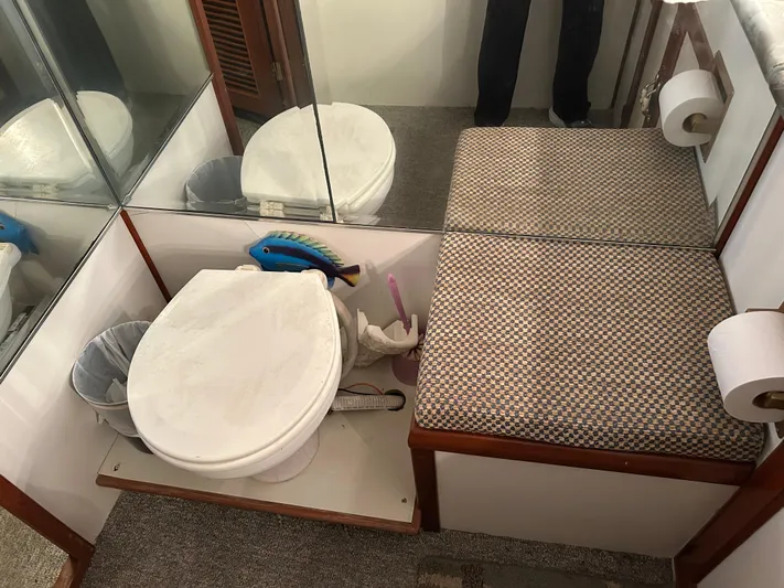 Broker Of Venice Yacht Photos Pics 1988 Sea Ranger aft cabin bathroom with toilet, cushioned bench, and mirrored walls.