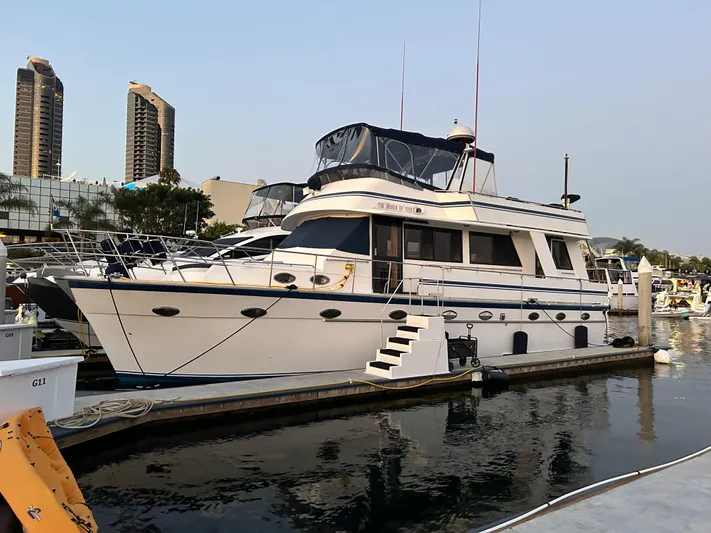 Broker Of Venice Yacht Photos Pics 1988 Sea Ranger aft cabin yacht docked at marina, with cityscape background.