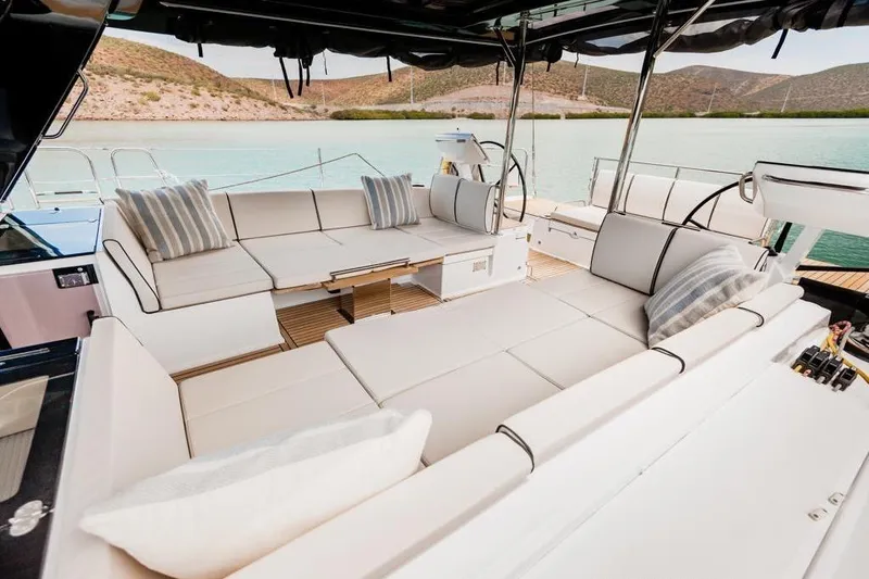 Dictador Yacht Photos Pics Luxurious seating area on 2022 Beneteau Oceanis Yacht 62, overlooking serene waters.