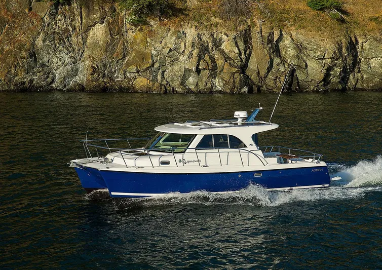  Yacht Photos Pics 2026 Aspen C100 boat cruising near rocky shoreline.