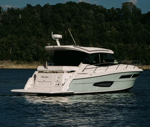  Yacht Photos Pics 2021 Regal 38 Grande Coupe yacht cruising on a serene lake with forested backdrop.