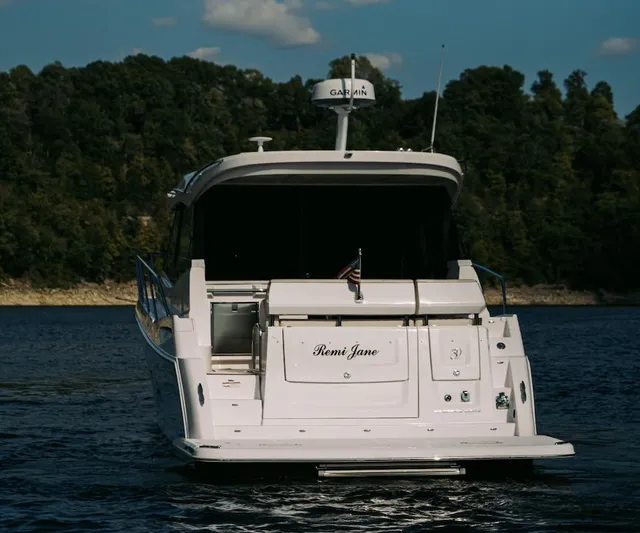  Yacht Photos Pics 2021 Regal 38 Grande Coupe yacht on a serene lake with forested background.