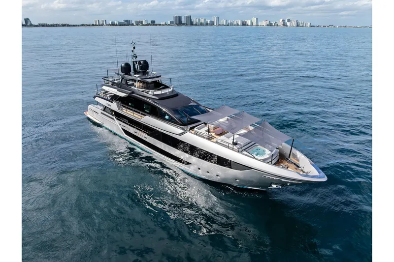 Euro Yacht Photos Pics Luxurious 2024 Riva 130' Bellissima yacht cruising on open water with city skyline backdrop.