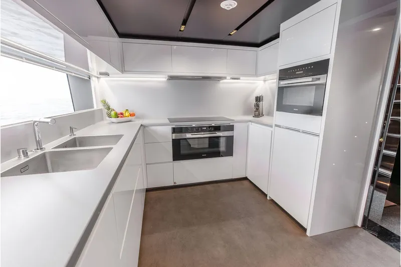 Euro Yacht Photos Pics Modern kitchen interior on 2024 Riva 130' Bellissima yacht, featuring sleek white cabinetry and appliances.