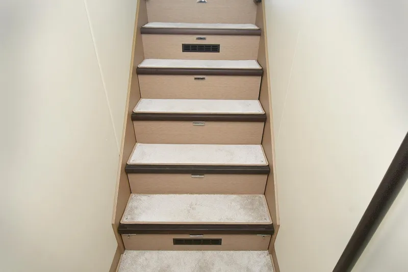  Yacht Photos Pics Staircase inside 2018 Prestige 560 Fly yacht, featuring carpeted steps and wooden accents.