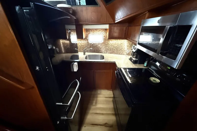 Luv'n Life Yacht Photos Pics Compact kitchen in 1989 Atlantic 47 Motor Yacht with modern appliances and wood cabinetry.