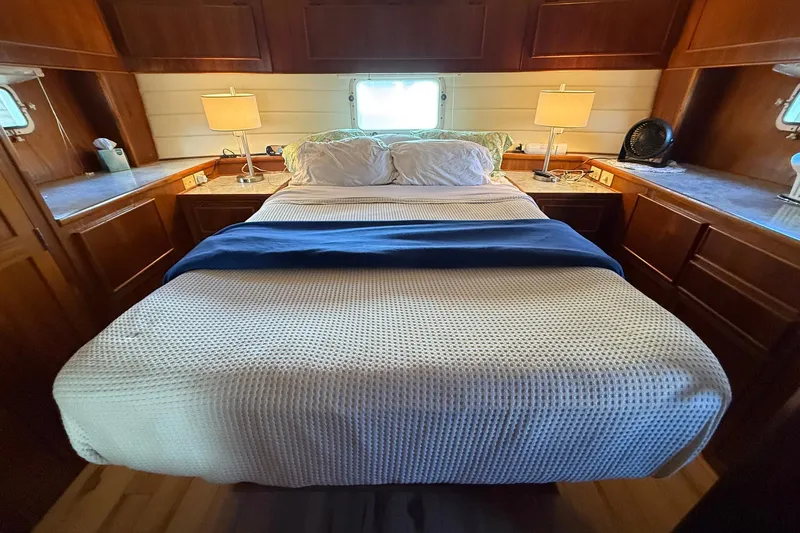 Luv'n Life Yacht Photos Pics Cozy bedroom interior of 1989 Atlantic 47 Motor Yacht with wooden cabinetry and soft lighting.