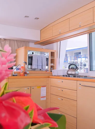 Larimar Yacht Photos Pics Modern kitchen interior of 2015 Lagoon 400 S2 catamaran with wooden cabinets and floral decor.