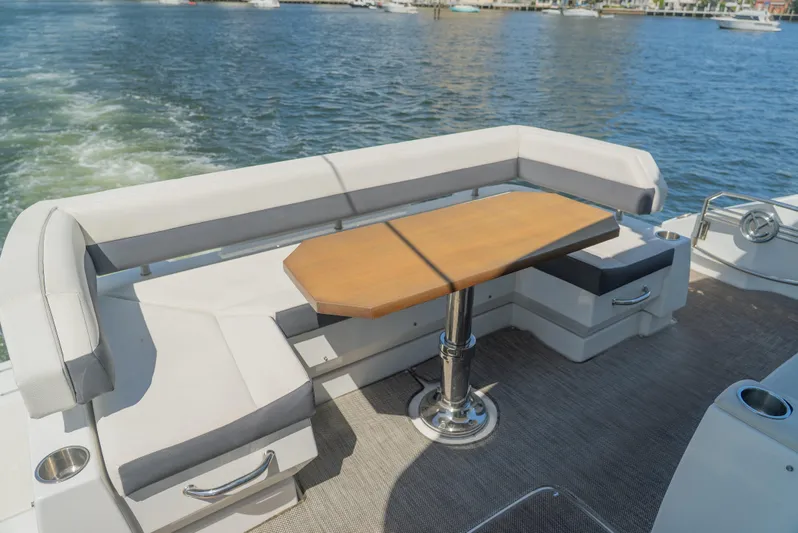 Duke Yacht Photos Pics Outdoor seating area on 2018 Cruisers Yachts 50 Cantius, featuring a wooden table and cushioned benches.