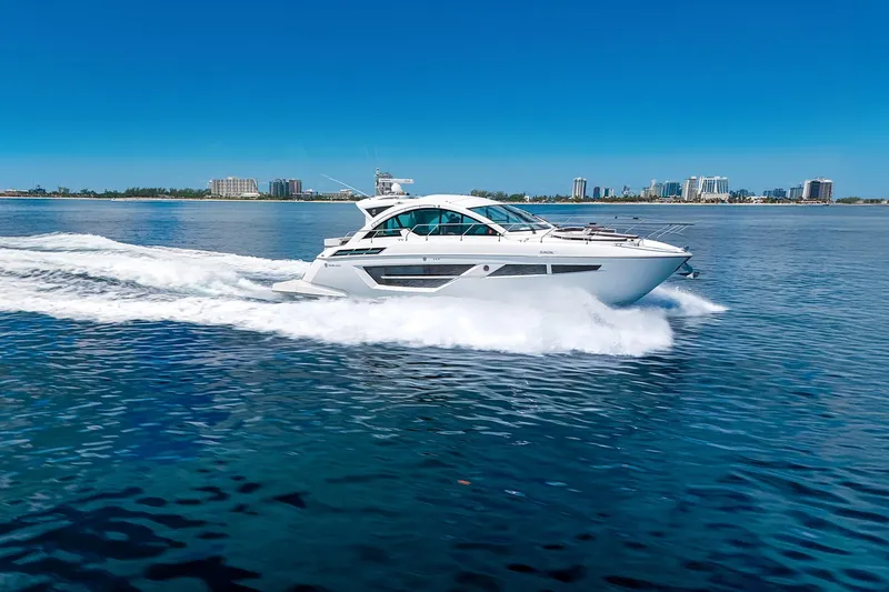 Duke Yacht Photos Pics 2018 Cruisers Yachts 50 Cantius cruising on open water with city skyline backdrop.