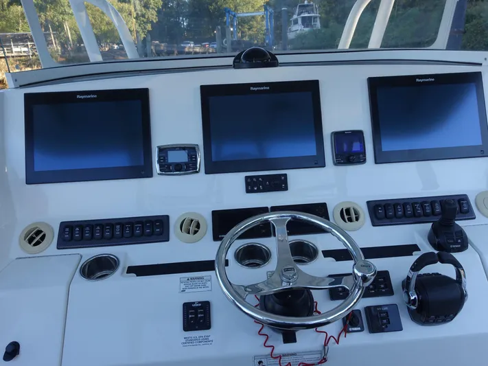  Yacht Photos Pics Control panel of a 2016 Regulator 41 boat with multiple screens and steering wheel.