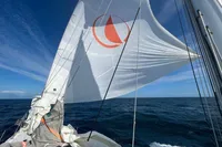 Sailing on a 1992 Devonport Challenge 67 yacht with full sails against a clear blue sky.