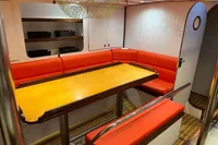 Interior of 1992 Devonport Challenge 67 yacht with red seating and wooden table.