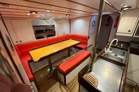 Interior of 1992 Devonport Challenge 67 yacht with red seating and wooden table.