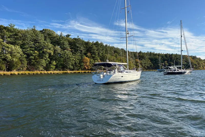 Sandman Yacht Photos Pics Sailboats on a scenic lake, featuring a 2004 Catalina 400 MkII, surrounded by lush trees.