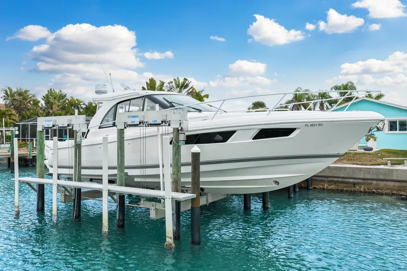  Yacht Photos Pics 2019 Intrepid 410 Evolution yacht on lift, docked by turquoise water, under blue sky.