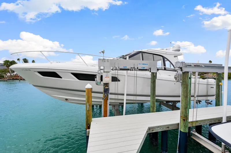  Yacht Photos Pics 2019 Intrepid 410 Evolution yacht on lift, docked over turquoise water.