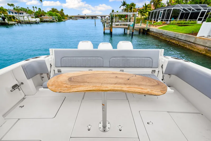  Yacht Photos Pics 2019 Intrepid 410 Evolution boat deck with wooden table, overlooking serene waterfront.