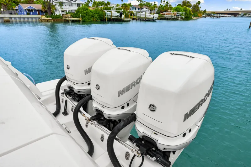  Yacht Photos Pics 2019 Intrepid 410 Evolution with triple Mercury outboard engines on a serene waterfront.