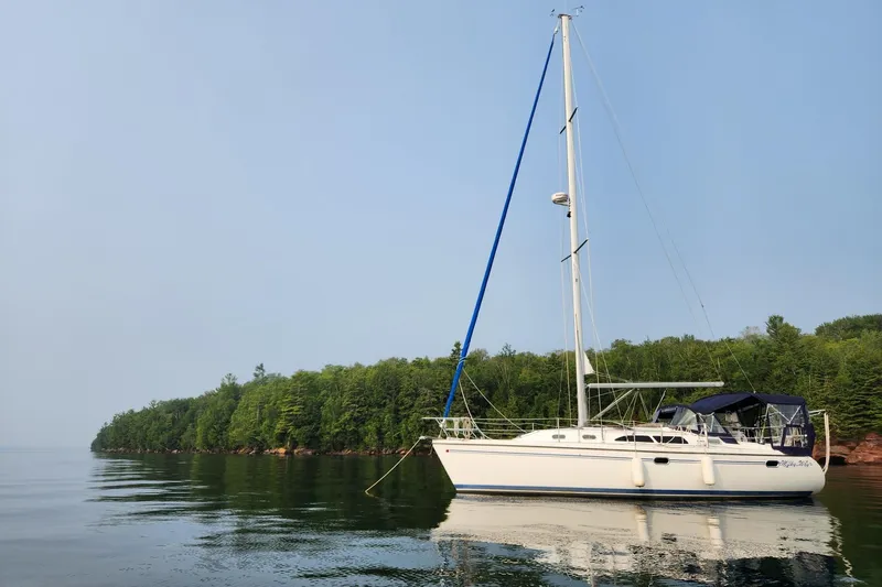 Milky Way Yacht Photos Pics Catalina 350 sailboat from 2004 anchored near a lush, green shoreline.
