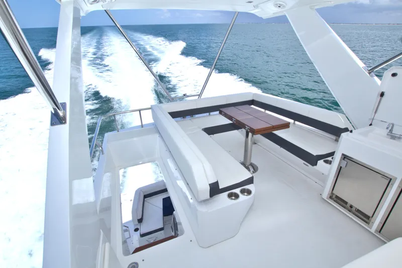Stepping Stone V Yacht Photos Pics Flybridge view of 2018 Cruisers Yachts 54 Fly, featuring sleek seating and ocean backdrop.