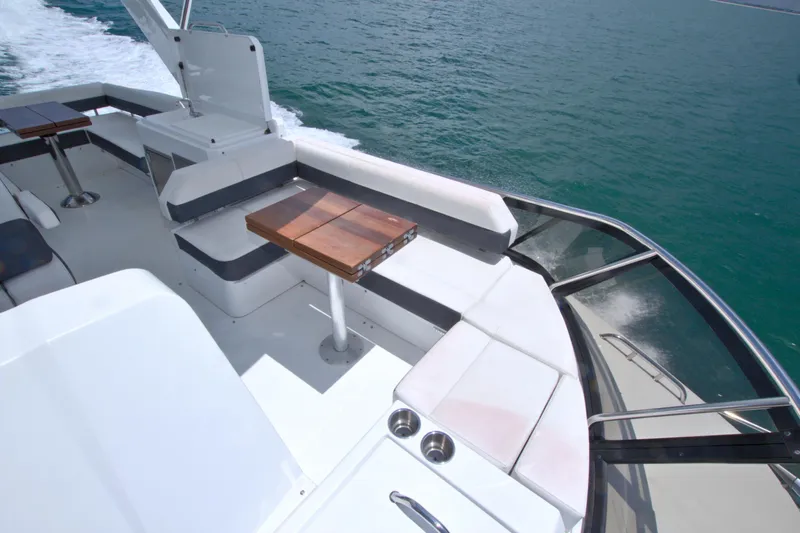Stepping Stone V Yacht Photos Pics 2018 Cruisers Yachts 54 Fly deck with seating and wooden tables on open water.