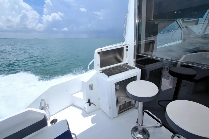 Stepping Stone V Yacht Photos Pics 2018 Cruisers Yachts 54 Fly deck with seating and grill, cruising on open water.