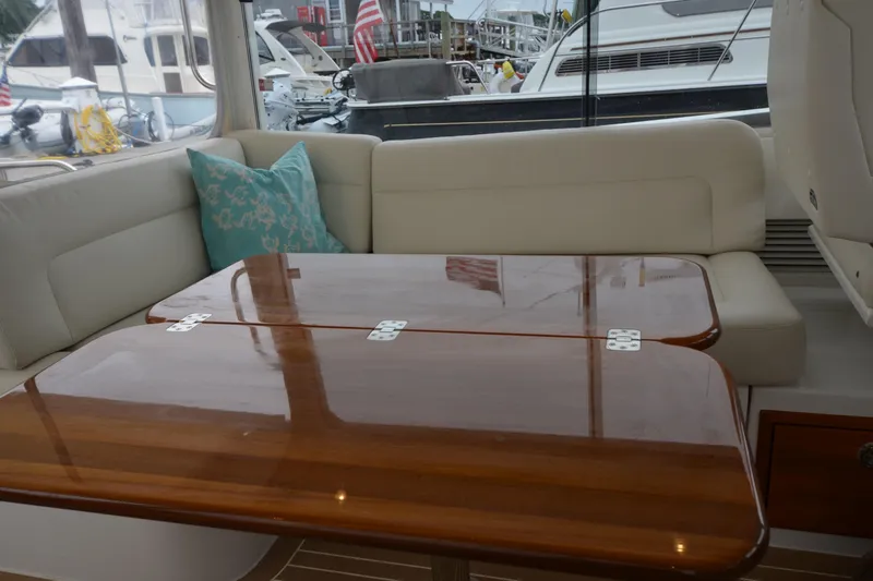 Whim Yacht Photos Pics Luxurious interior of 2020 MJM 43z yacht with polished wooden table and cushioned seating.