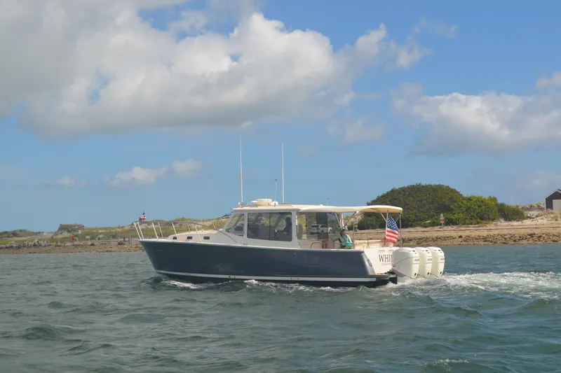Whim Yacht Photos Pics 2020 MJM 43z boat cruising on water with American flag, under blue sky.