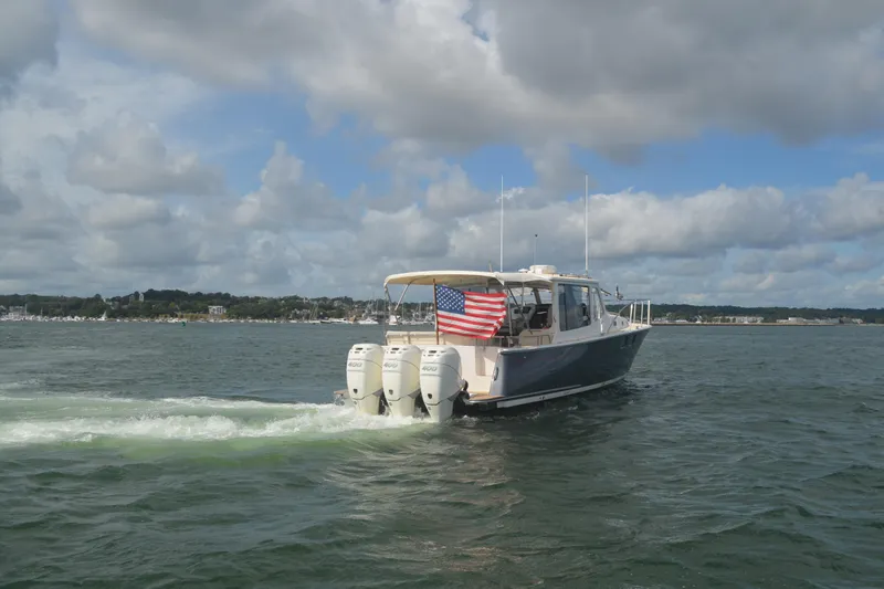 Whim Yacht Photos Pics 2020 MJM 43z boat cruising on water with American flag, under cloudy sky.