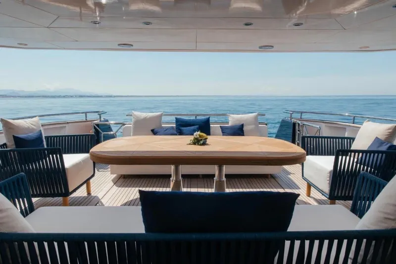 Lady In Blue Yacht Photos Pics Luxurious Clemna Rossi Navi 135 yacht deck with elegant seating, ocean view, and wooden table.
