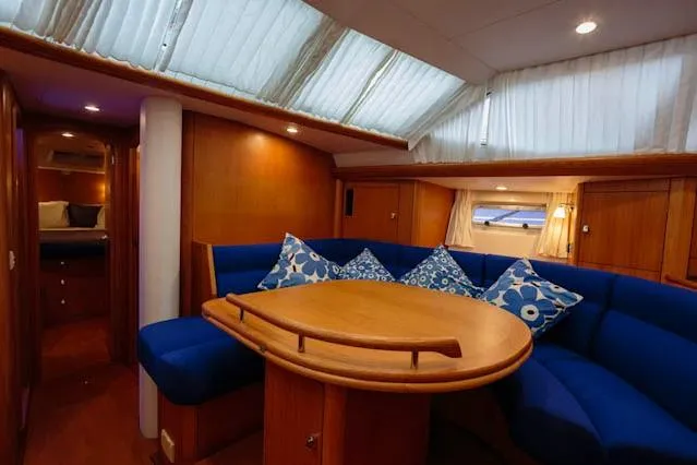 Making Time Yacht Photos Pics Luxurious interior of 2004 Oyster 53 yacht with blue seating and wooden table.